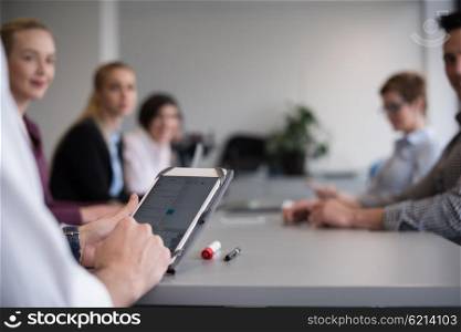 close up of businessman hands using tablet, people group in office meeting room blurred in backgronud