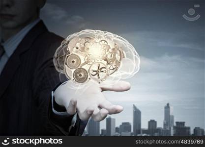 Close up of businessman holding human brain with working gears. Process of thinking