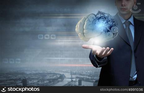 Close up of businessman holding human brain with working gears. Process of thinking