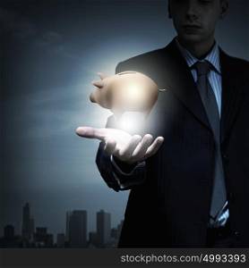 Close up of businessman holding piggy bank in hand. Protect your savings