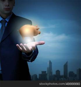 Close up of businessman holding piggy bank in hand. Protect your savings