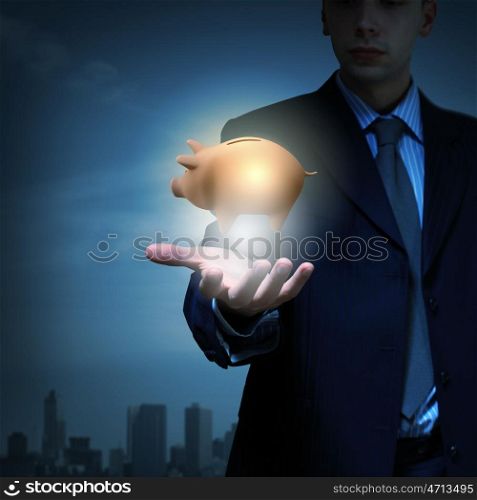 Close up of businessman holding piggy bank in palm. Protect your money