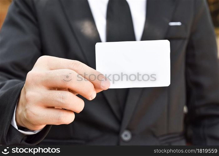 Close-up of businessman holding white piece of paper. Selective focus hand.