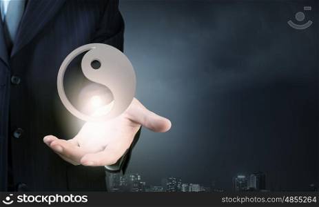 Close up of businessman holding yin yang symbols in palm. Yin yang phylosophy