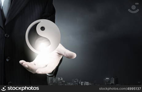 Close up of businessman holding ying yan symbol in palm. Symbol of ying yan