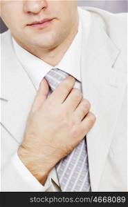 Close up of businessman in a business suit correcting his tie. Business tie