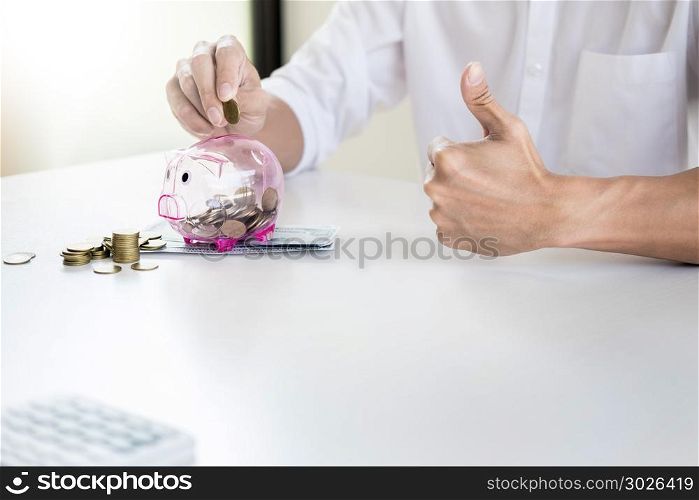 Close up of Businessman putting coin into small piggy bank , The concept of saving money and investment.. Close up of Businessman putting coin into small piggy bank , The