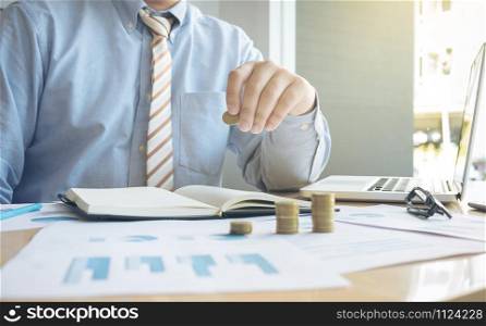 Close-up of Businessman putting coin to rising stack of coins.