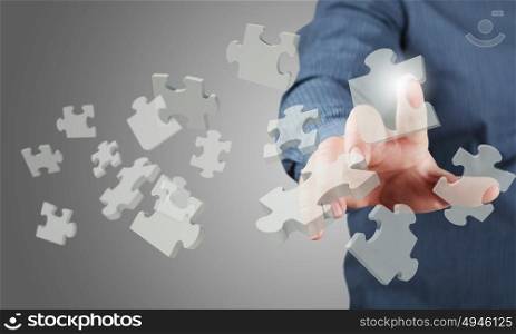Close up of businessman&rsquo;s hand touching abstract puzzle piece. Finger touching icon