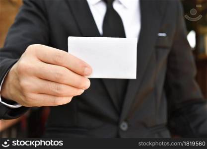 Close-up of businessman showing white piece of paper. Selective focus hand.