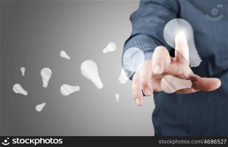 Close up of businessman touching with finger virtual light bulb. Concept of idea or creativity