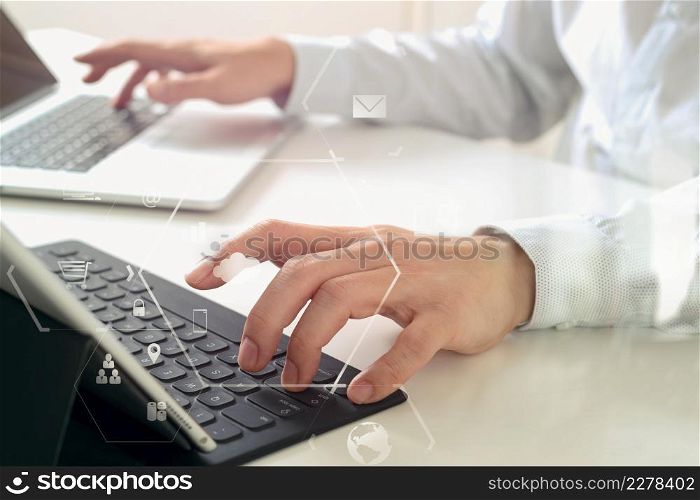 close up of businessman typing keyboard with laptop computer and digital tablet on white desk in modern office with VR icon diagram
