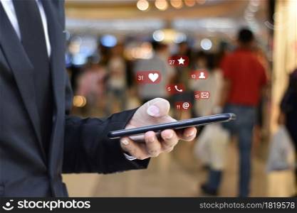 Close up of businessman using mobile smartphone with social media icons over blurred airport station background. Business, technology or social network concept.