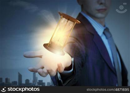 Close up of businessman with sandglass presenting time concept. Respect your time