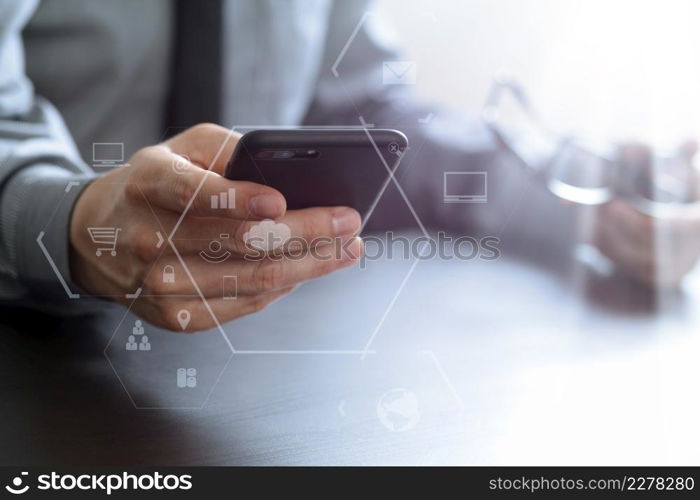 close up of businessman working with mobile phone and eyeglass on wooden desk in modern office with virtual reality icon diagram