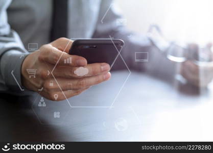 close up of businessman working with mobile phone and eyeglass on wooden desk in modern office with virtual reality icon diagram