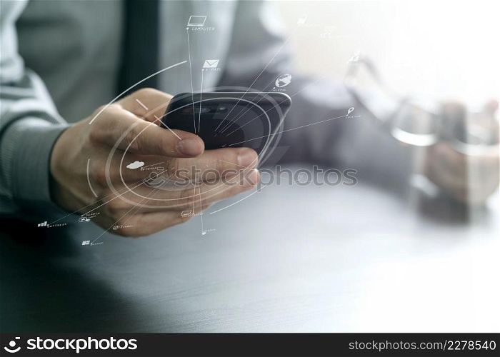 close up of businessman working with mobile phone and eyeglass on wooden desk in modern office with virtual reality icon diagram