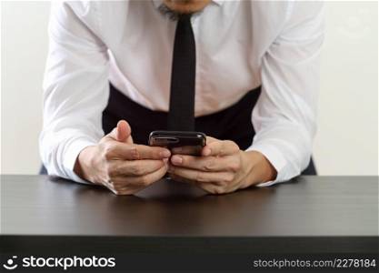 close up of businessman working with mobile phone and sitting on the chair in modern office