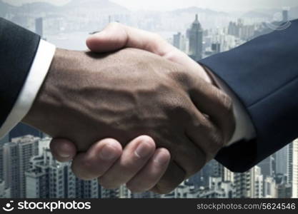 Close up of businessmen shaking hands with cityscape in the background