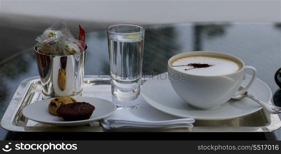 Close-up of Cappuccino with cookies and glass of water on a tray, Marrakesh, Morocco