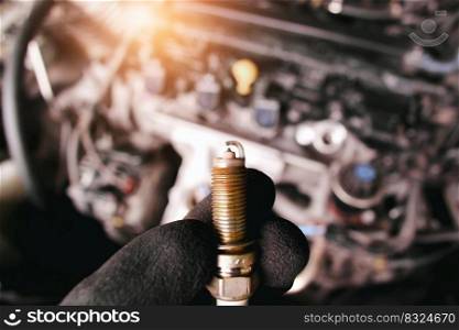 Close up of car iridium spark plugs damaged by heavy use of the car engine ignition system, engine compartment blurred on background with sunlight
