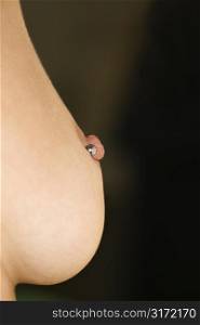 Close up of Caucasian female young adult breast with pierced nipple.