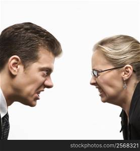 Close-up of Caucasian mid-adult man and woman staring at each other with hostile expressions.