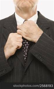 Close-up of Caucasian middle-aged businessman straightening necktie.