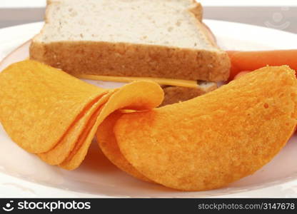 Close up of cheese flavored chips with turkey sandwich and carrots in background.