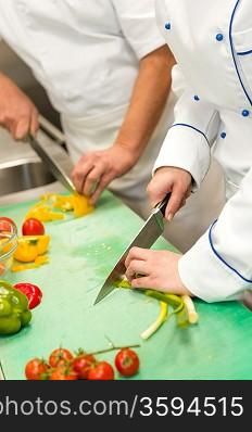 Close up of chefs cutting vegetables in hotel&acute;s kitchen