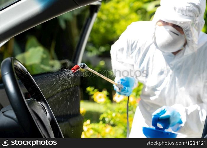 Close up of chemical alcohol spray cleaning inside car to disinfect and decontaminate coronavirus covid-19 by specialist cleaner wearing personal protective equipment PPE. New normal Hygiene concept.