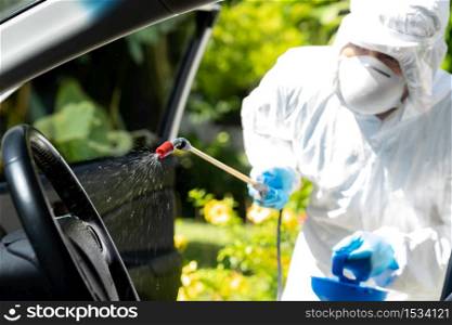 Close up of chemical alcohol spray cleaning inside car to disinfect and decontaminate coronavirus covid-19 by specialist cleaner wearing personal protective equipment PPE. New normal Hygiene concept.