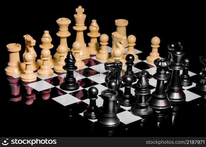 Close up of Chess pieces on a reflective mirror board surface with a plain black background
