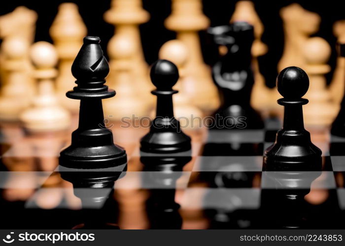 Close up of Chess pieces on a reflective mirror board surface with a plain black background