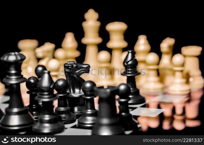 Close up of Chess pieces on a reflective mirror board surface with a plain black background