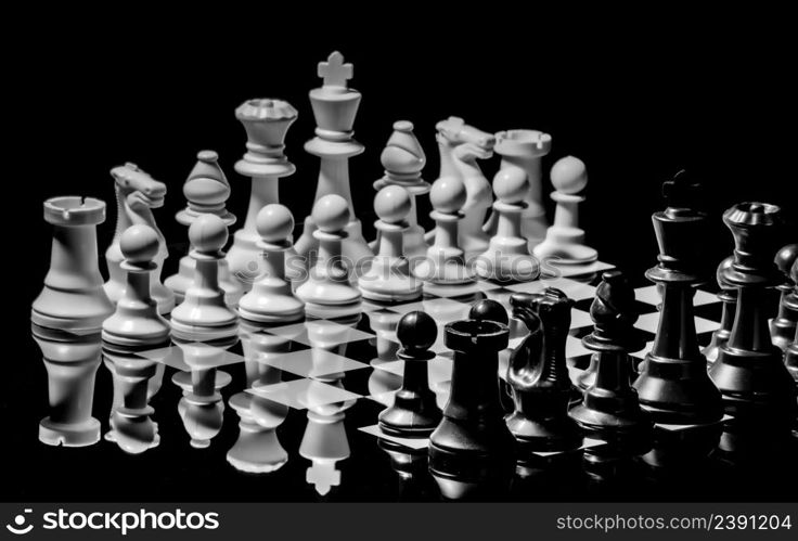 Close up of Chess pieces on a reflective mirror board surface with a plain black background