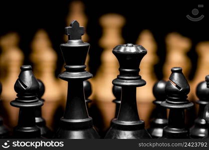 Close up of Chess pieces on a reflective mirror board surface with a plain black background