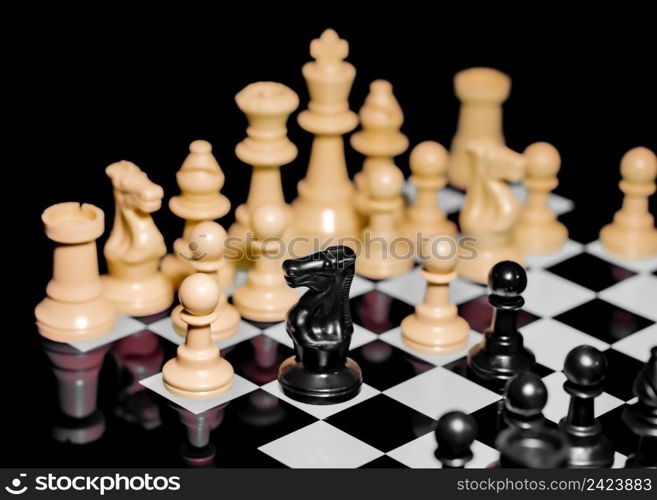 Close up of Chess pieces on a reflective mirror board surface with a plain black background