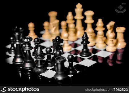 Close up of Chess pieces on a reflective mirror board surface with a plain black background