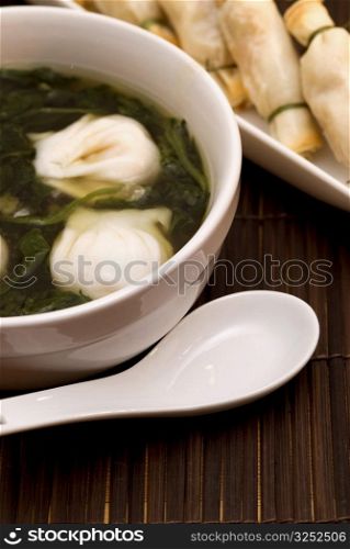 Close-up of Chinese dumplings in a bowl with sushi in the background