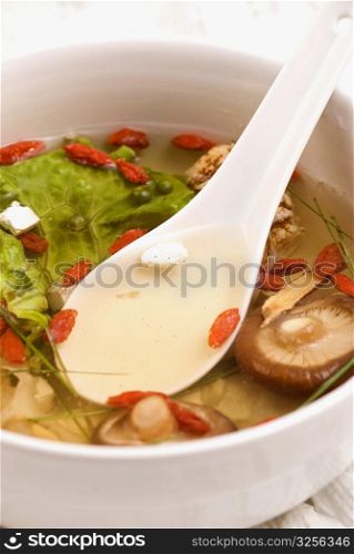 Close-up of Chinese soup with vegetables, mushrooms and pomegranate seeds in a bowl