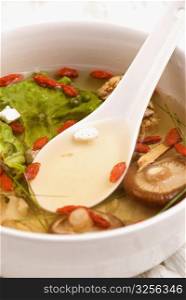 Close-up of Chinese soup with vegetables, mushrooms and pomegranate seeds in a bowl