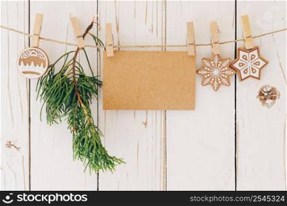 Close up of christmas decoration and blank paper card hanging on wood background.