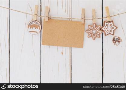 Close up of christmas decoration and blank paper card hanging on wood background.