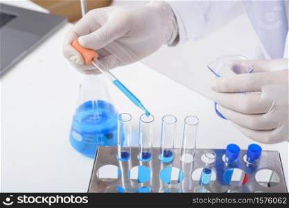 close up of cientist is testing and researching some blue liquid chemical in laboratory isolated white background.