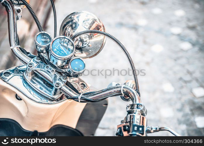 Close up of classic motorcycle shinny handlebar and chrome motorcycle speedometer on a street.. Close up of classic motorcycle shinny handlebar speedometer