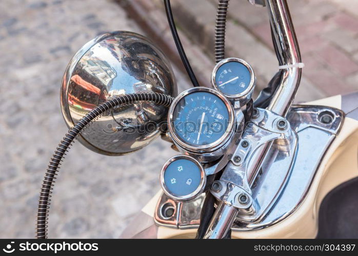 Close up of classic motorcycle shinny handlebar and chrome motorcycle speedometer on a street.. Close up of classic motorcycle shinny handlebar speedometer