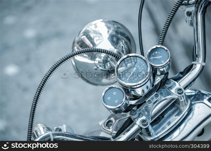 Close up of classic motorcycle shinny handlebar and chrome motorcycle speedometer on a street.. Close up of classic motorcycle shinny handlebar speedometer