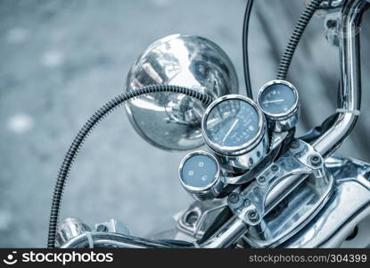Close up of classic motorcycle shinny handlebar and chrome motorcycle speedometer on a street.. Close up of classic motorcycle shinny handlebar speedometer