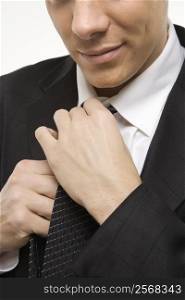 Close-up of Claucasian mid-adult man straightening necktie.
